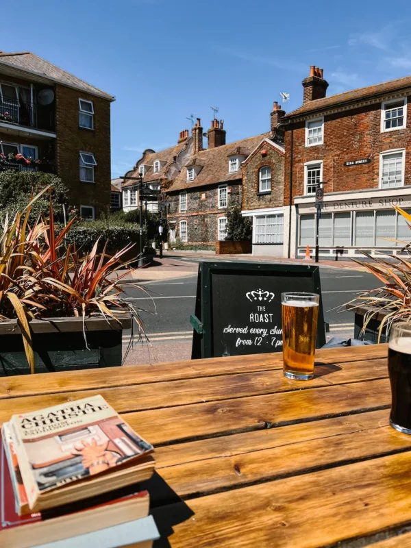a pint of beer and books on a wooden table